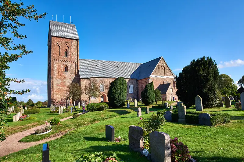 nieblum foehr kirche friedhof Die Kirche mit Friedhof im Vordergrund von Nieblum auf Föhr. Bei Sonnenschein und blauem Himmel.