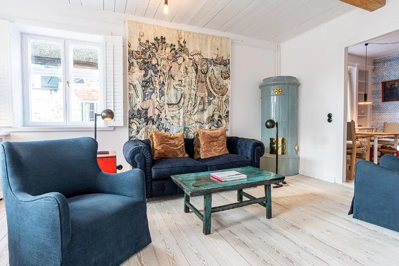 soennes stuuv ferienwohnung nieblum foehr Blick in das gemütliche Wohnzimmer von Sönnes Stuuv mit Sessel und Coach in blau und Kamin.
