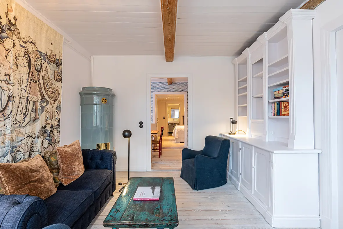 soennes stuuv ferienwohnung nieblum foehr Blick in das gemütliche Wohnzimmer von Sönnes Stuuv mit Sessel und Couch in blau sowie Kamin und deckenhohes Sideboard.